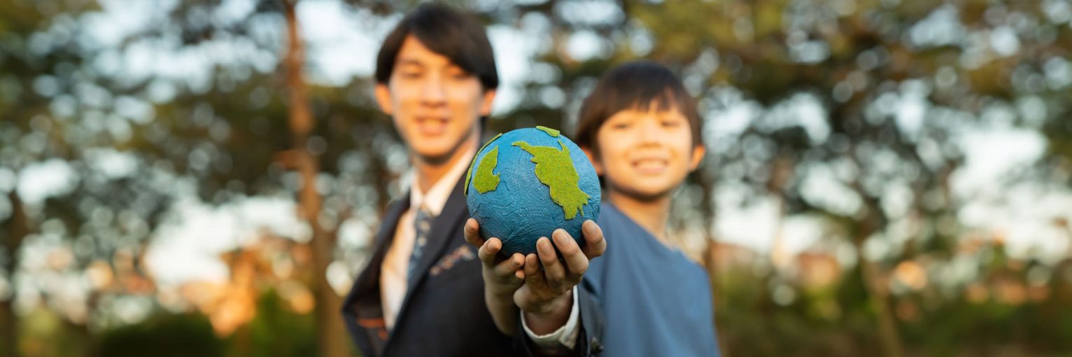 Focus panorama Earth with blur asian boy and businessman holding globe together as Earth day concept. Corporate social responsible to make greener environmental for sustainable future generation. Gyre